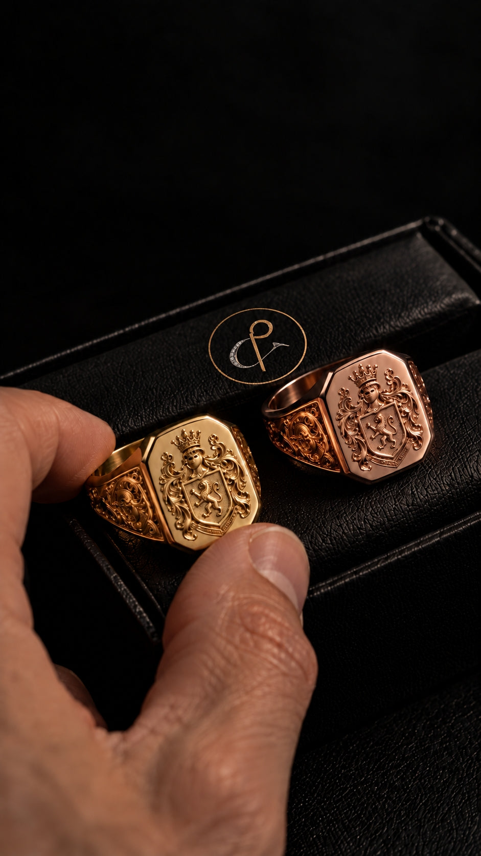 Anillos heráldicos dorado y rosado con escudo en relieve sobre estuche de DP&C Joyas